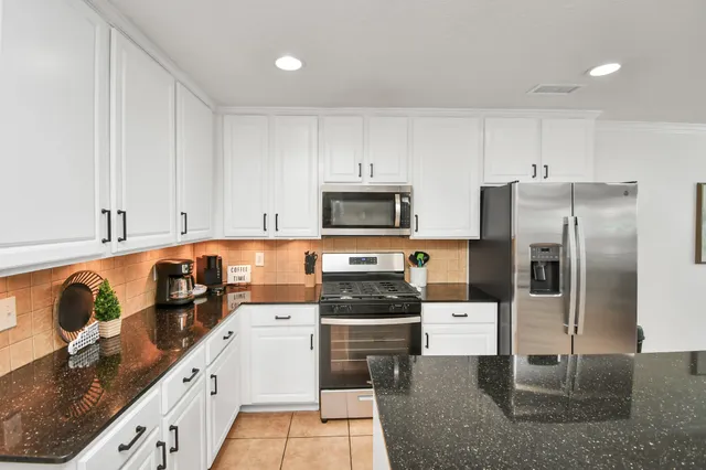 a large kitchen with granite countertop a large counter top stainless steel appliances and a counter space