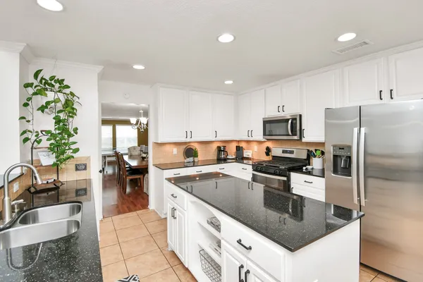 a kitchen with stainless steel appliances granite countertop a sink a stove and cabinets
