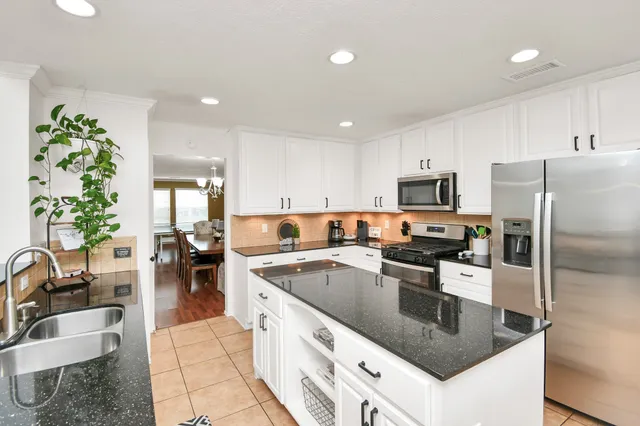 a kitchen with stainless steel appliances granite countertop a sink a stove and cabinets