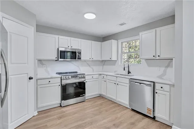 a kitchen with cabinets stainless steel appliances and a window