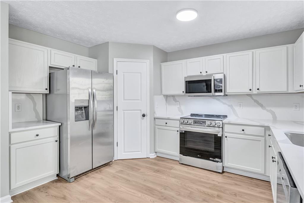 4061 Jewel Terrace Conley, GA 30288 - Photo 13 of 36 a kitchen with cabinets stainless steel appliances and wooden floor