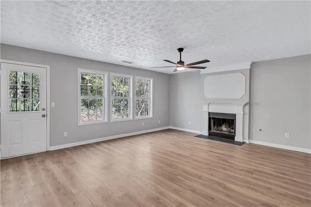 an empty room with windows a fireplace and wooden floor