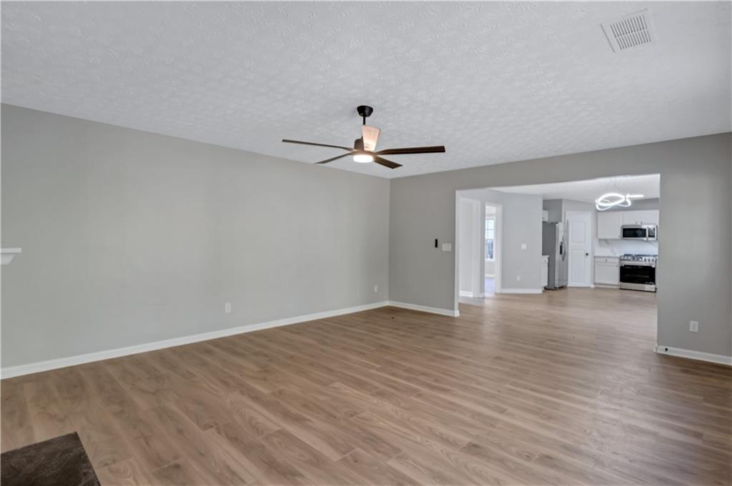 4061 Jewel Terrace Conley, GA 30288 - Photo 15 of 36 a view of an empty room with wooden floor and a ceiling fan