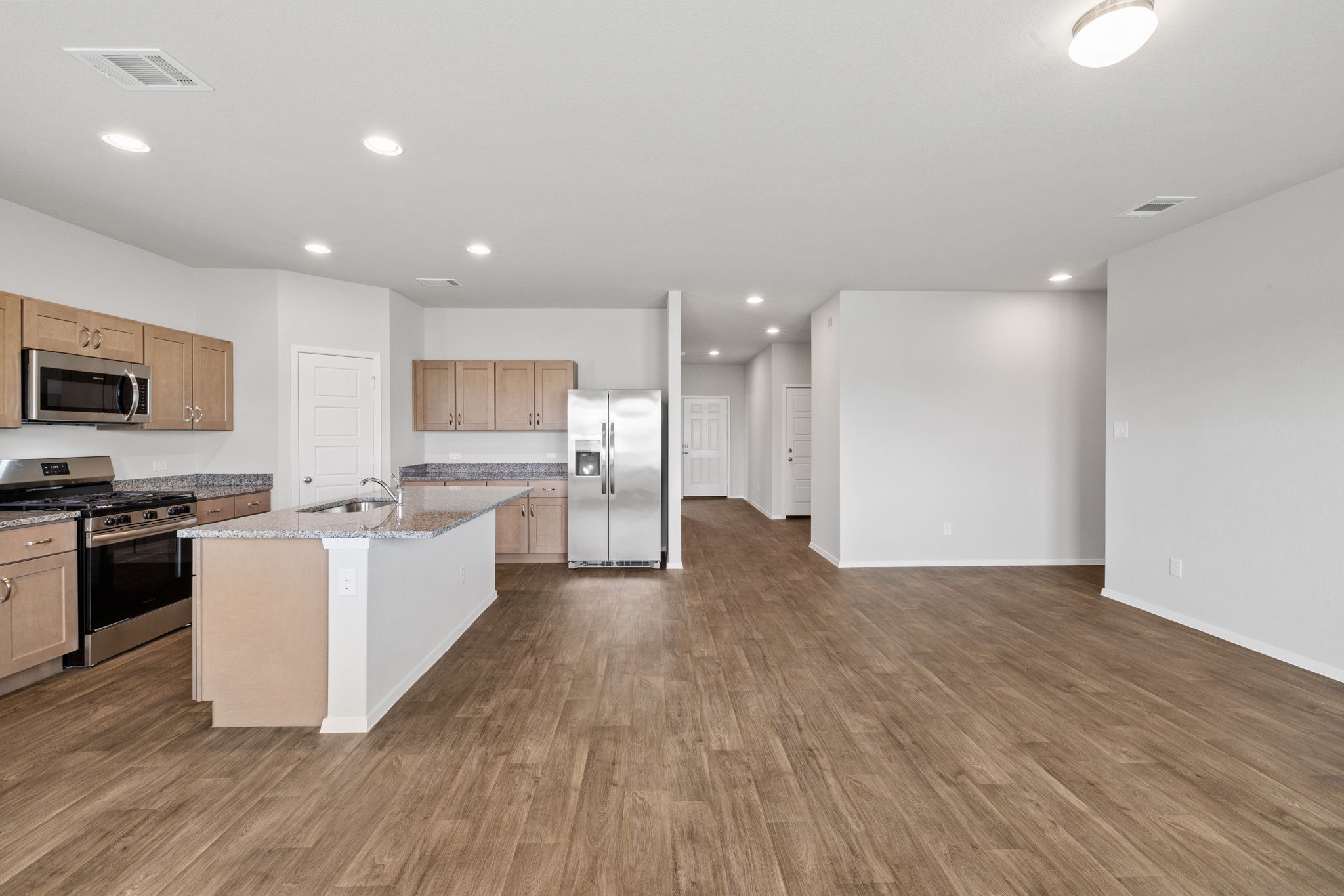 2460 Winding Creek Road Kyle, TX 78640 - Photo 20 of 20 A contemporary kitchen and living area featuring an inviting open floor plan with warm wood flooring.