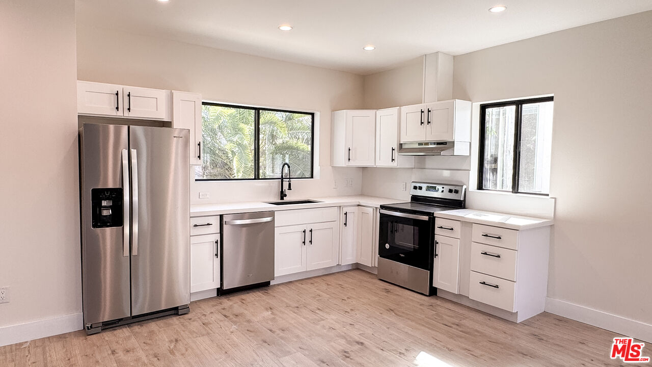 19557 Calvert Street Tarzana, CA 91335 - Photo 4 of 11 a kitchen with white cabinets and white appliances