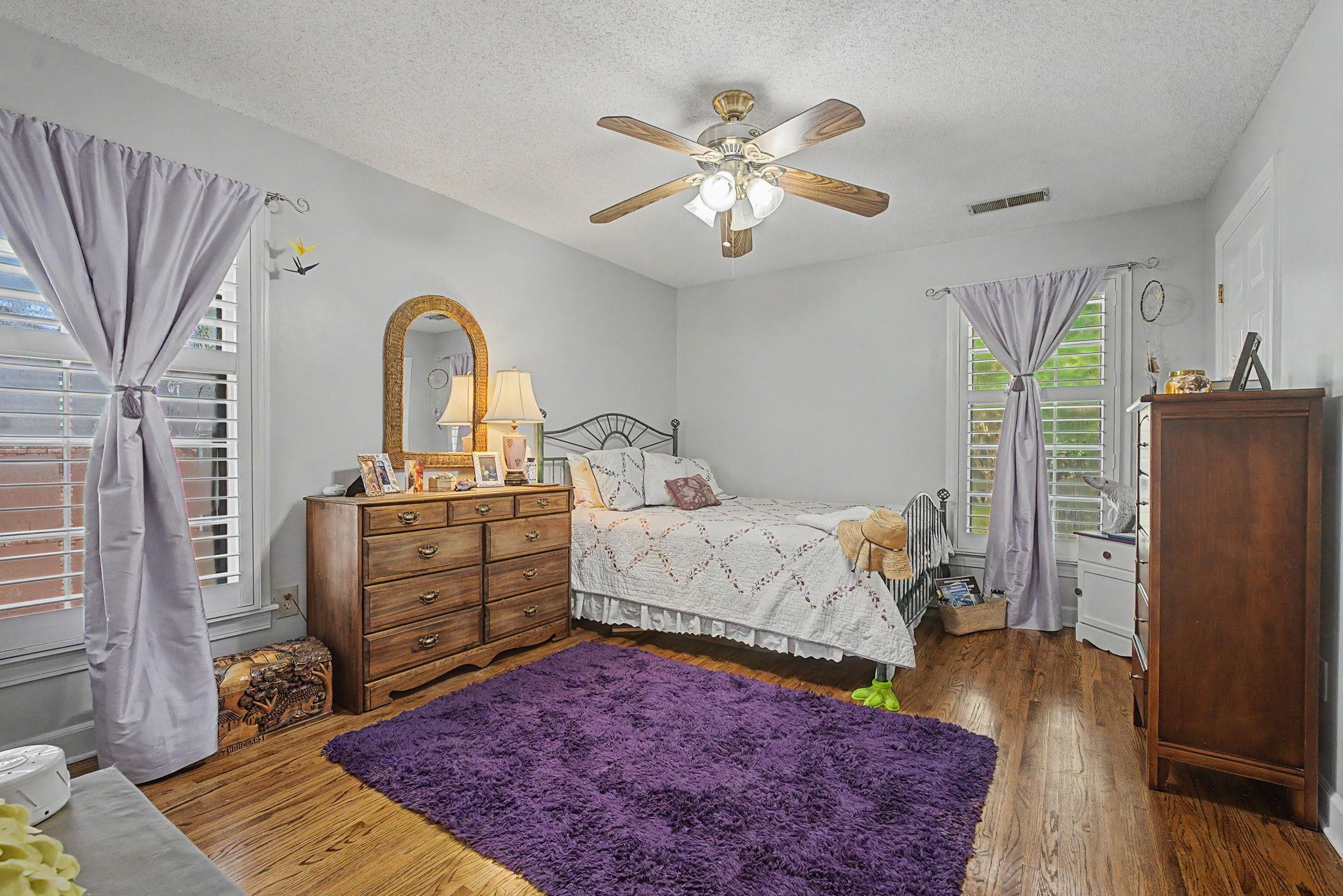 1929 Miller Farms Road Germantown, TN 38138 - Photo 26 of 40 Bedroom space featuring wood-finish flooring, two large windows with plantation shutters, a ceiling fan with integrated lighting, and light-toned wall finishes