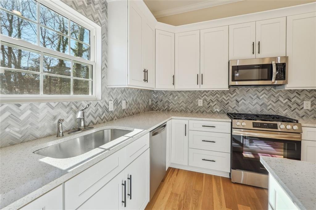1620 Derry Avenue Southwest Atlanta, GA 30310 - Photo 16 of 47 a kitchen with stainless steel appliances granite countertop a sink and cabinets with wooden floor