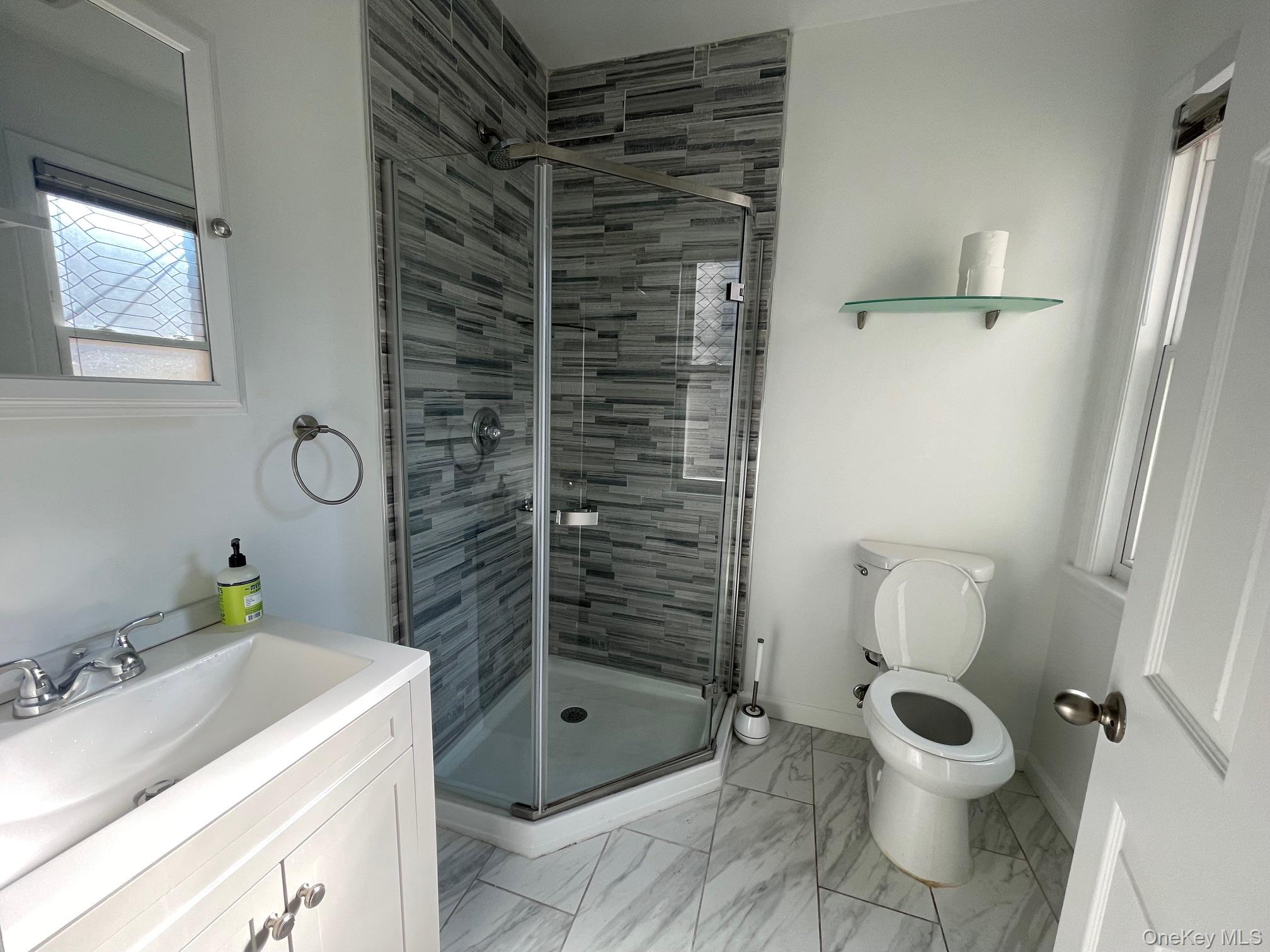 1049 Main Street, Unit 2 Peekskill, NY 10566 - Photo 4 of 9 a bathroom with a granite countertop toilet a sink and a shower