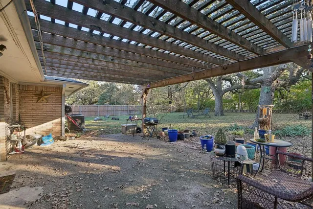 a view of a patio with table and chairs under an umbrella with a big yard