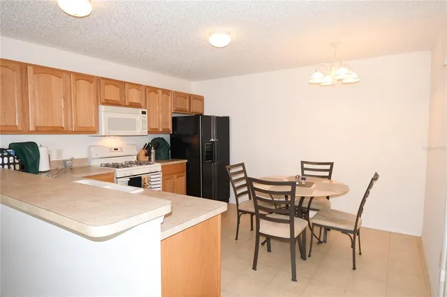 a kitchen with a dining table chairs and refrigerator
