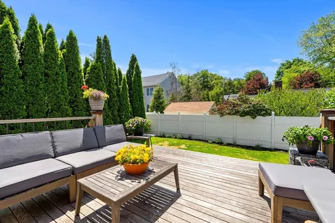 a view of a patio with couches table and chairs with wooden fence and plants