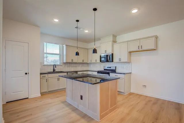 a kitchen with stainless steel appliances granite countertop a sink stove and refrigerator