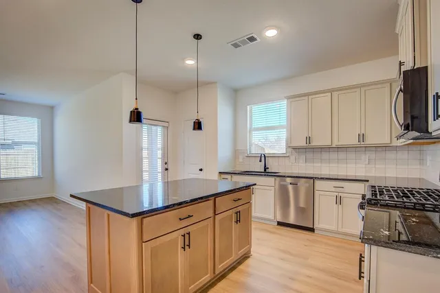 a kitchen with stainless steel appliances granite countertop a sink a stove and a refrigerator