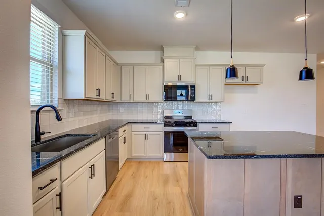 a kitchen with stainless steel appliances granite countertop a sink a stove and a refrigerator