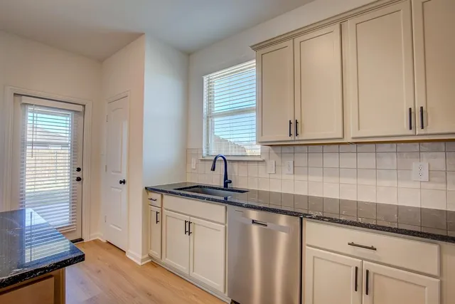 a kitchen with granite countertop white cabinets and a window