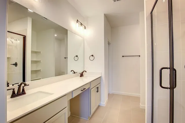 a en suite bathroom with a double vanity sink a mirror and shower