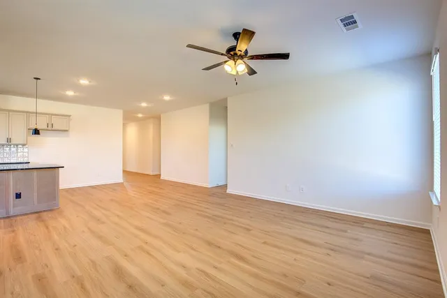 a view of empty room with wooden floor and ceiling fan