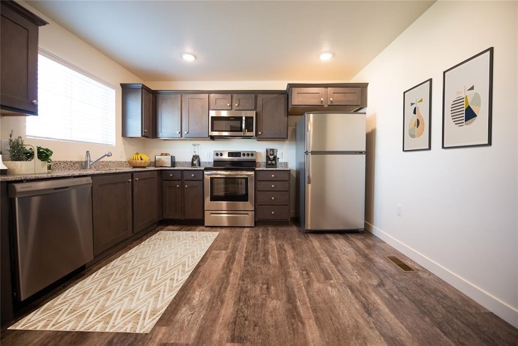 12603 Telge Road, Unit 7D Cypress, TX 77429 - Photo 10 of 19 a kitchen with stainless steel appliances granite countertop a refrigerator a stove top oven a sink and dishwasher with wooden floor