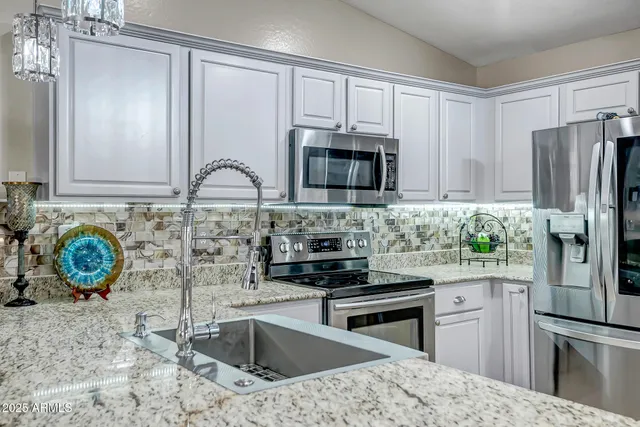 a kitchen with stainless steel appliances granite countertop a sink stove and refrigerator