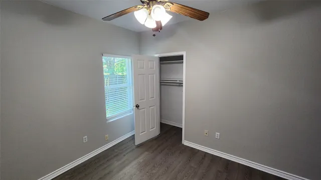 an empty room with windows and fan