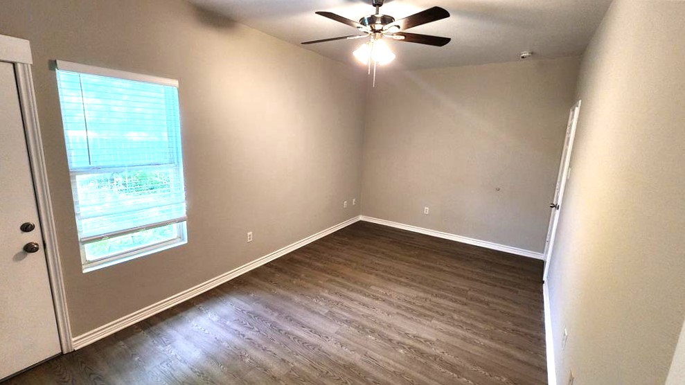 605 Martin Luther King Boulevard, Unit A Elgin, TX 78621 - Photo 16 of 18 an empty room with wooden floor fan and windows