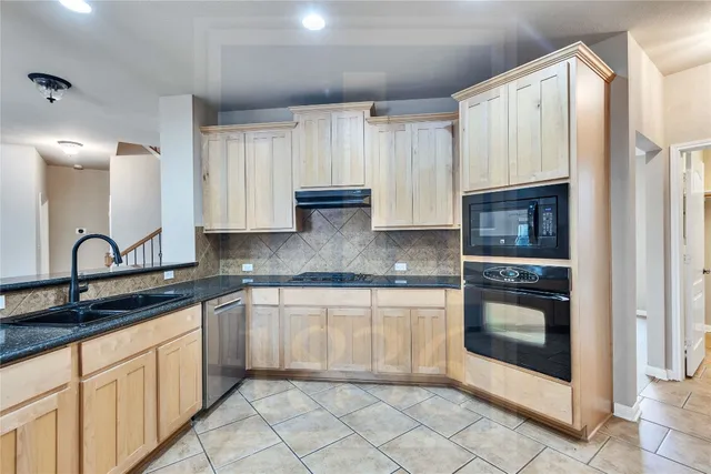 a kitchen with granite countertop a sink stainless steel appliances and cabinets