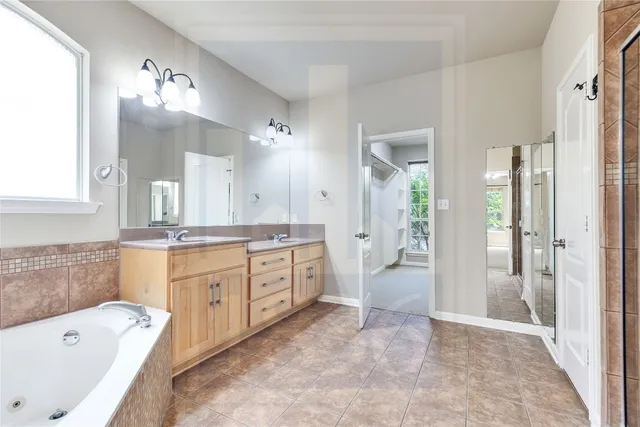 a bathroom with a bathtub a double vanity sink and a large mirror