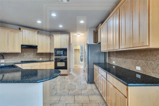 a large kitchen with granite countertop a sink a counter top space appliances and cabinets