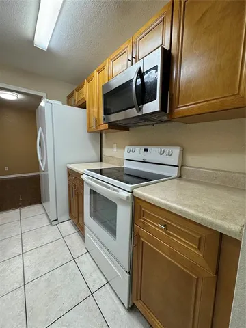 a kitchen with granite countertop a refrigerator and a stove top oven