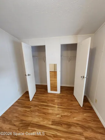 a view of an empty room with wooden floor and closet