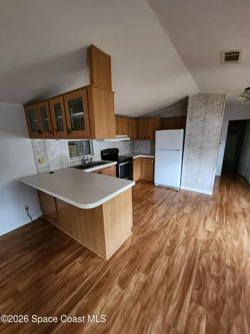 a living room with stainless steel appliances kitchen island hardwood floor and a large window