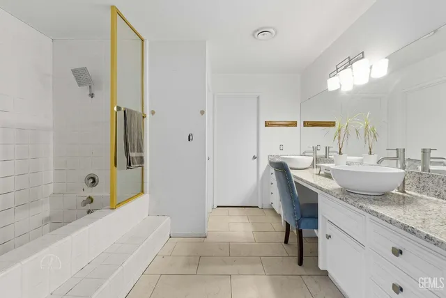 a bathroom with a granite countertop sink a mirror and a bathtub