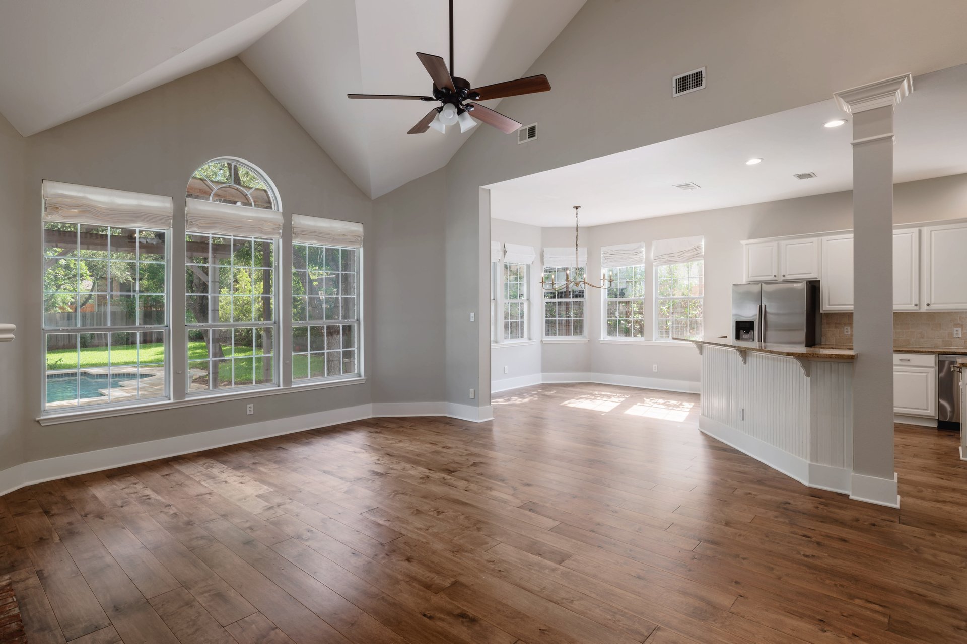 5512 Ballenton Lane Austin, TX 78739 - Photo 10 of 40 A spacious living area with vaulted ceilings and rich hardwood flooring flows into a sunlit kitchen and dining space.