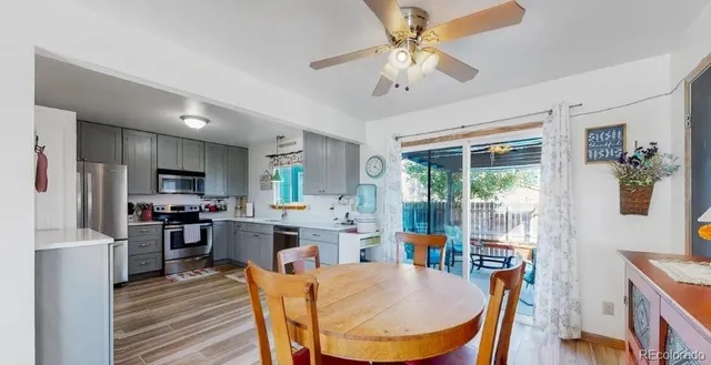 a kitchen with stainless steel appliances kitchen island granite countertop a refrigerator a stove top oven a sink dishwasher a dining table and chairs with wooden floor