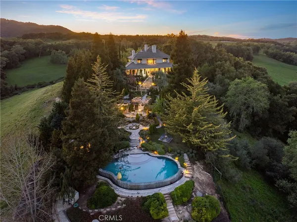 an aerial view of a house with outdoor space and trees all around