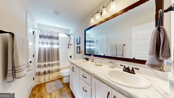 a bathroom with a double vanity sink toilet mirror and shower