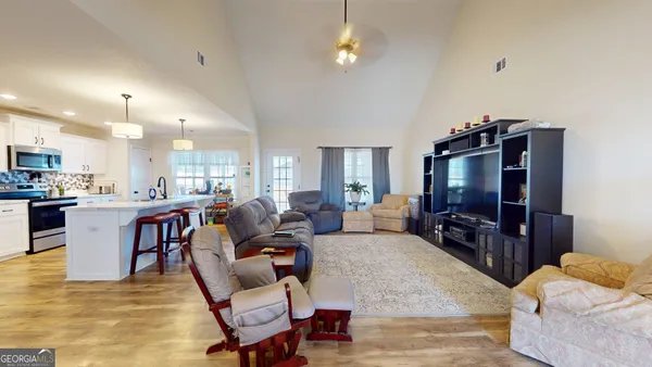 a living room with furniture a flat screen tv and kitchen view
