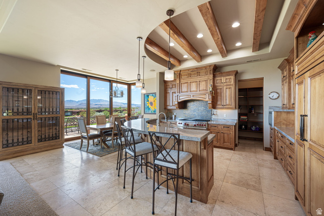2331 West Entrada Trail, Unit 61 St. George, UT 84770 - Photo 11 of 69 Gourmet kitchen and dining area featuring a curved island, recessed ceiling with wood beams, light wood-finish cabinetry, a large built-in pantry, and expansive windows showcasing a distant mountain range