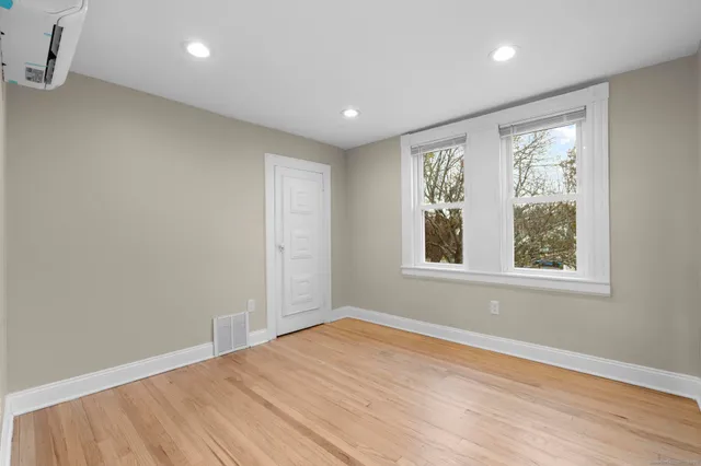 an empty room with wooden floor and windows