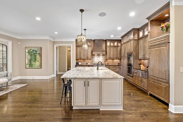 a large kitchen with stainless steel appliances kitchen island granite countertop a table chairs and a refrigerator