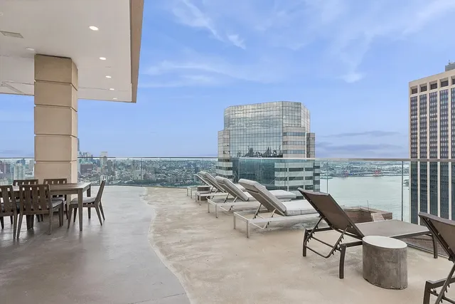 a living room with couches a coffee table and chairs with the view of kitchen