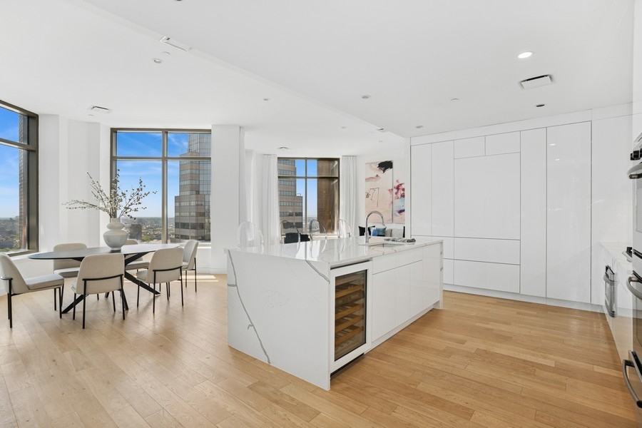 75 Wall Street, Unit PHD2 Manhattan, NY 10005 - Photo 14 of 15 a large white kitchen with wooden floor and stainless steel appliances