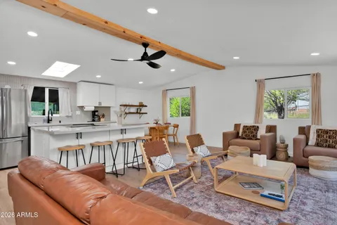 a living room with furniture kitchen view and a wooden floor