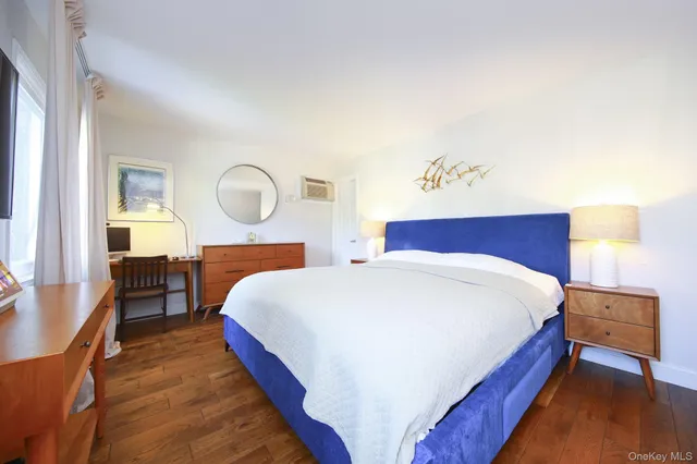 a bedroom with bed and a large mirror with wooden floor