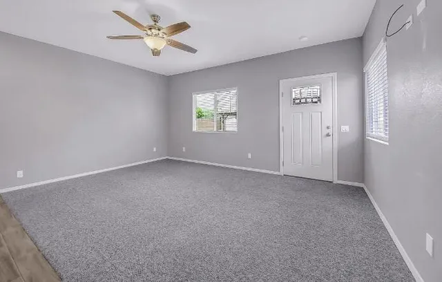 an empty room with windows and fan