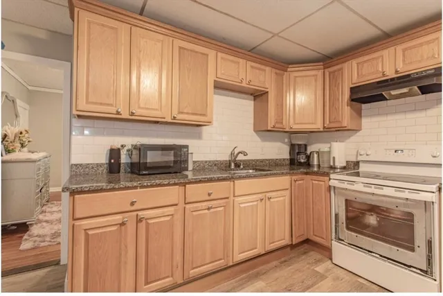 a kitchen with granite countertop stainless steel appliances white cabinets granite counter tops and a wooden floors