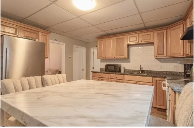 a large white kitchen with kitchen island granite countertop a sink and cabinets
