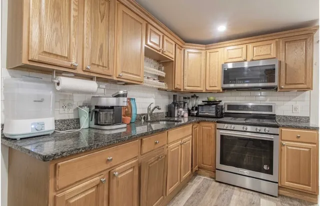 a kitchen with granite countertop a sink stainless steel appliances and cabinets
