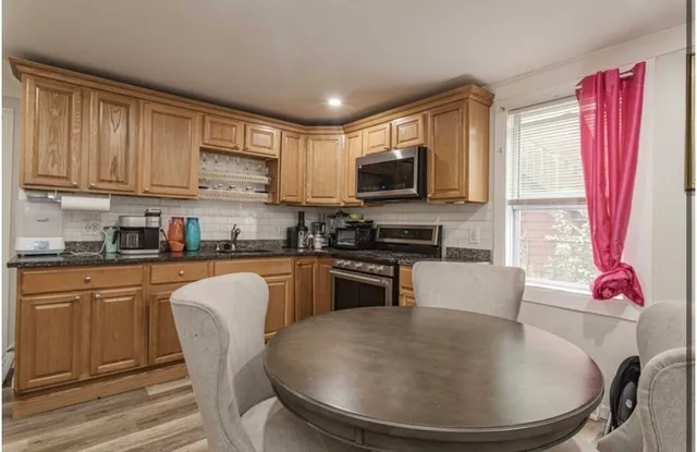 a kitchen with stainless steel appliances granite countertop a stove a sink a microwave a dining table and chairs