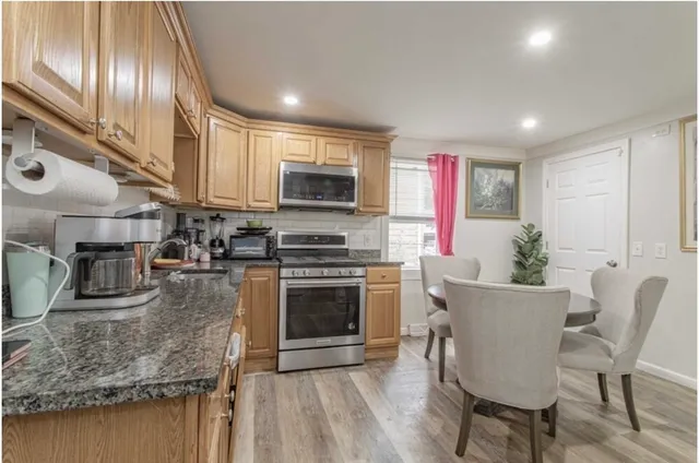 a kitchen with stainless steel appliances granite countertop a stove top oven a sink and a chairs